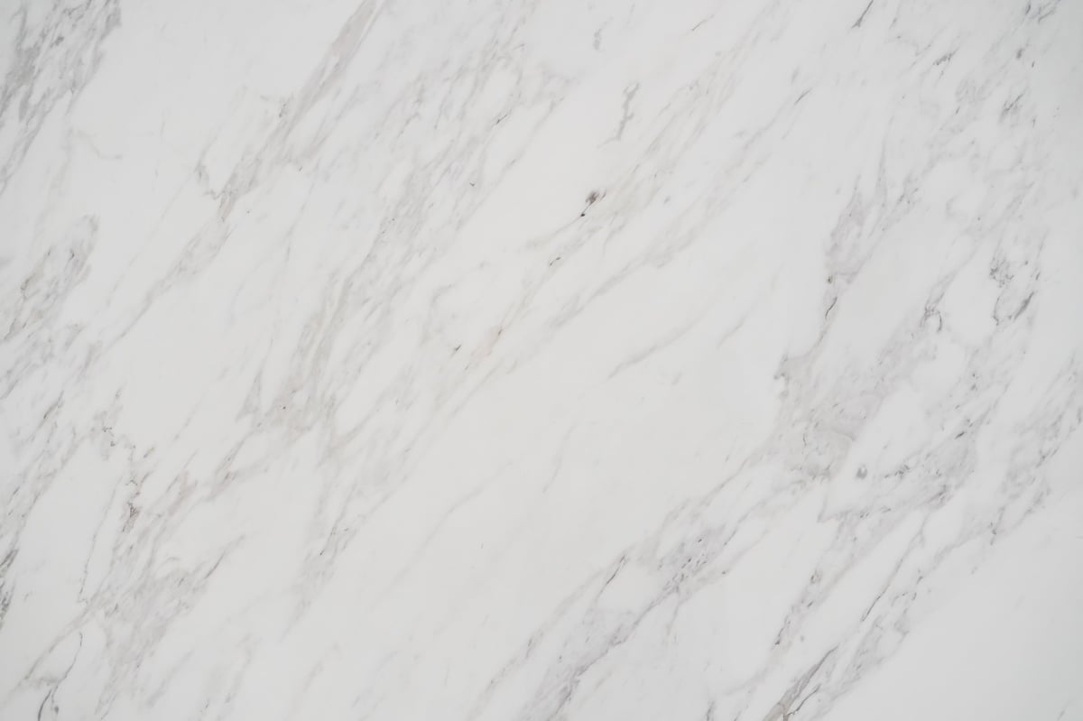 Close-up of a polished white marble countertop slab with grey veining after sealing